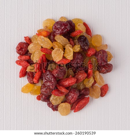 Top view of circle of mixed dried fruits against white vinyl background.