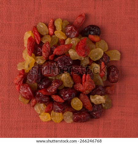 Top view of circle of mixed dried fruits against red vinyl background.