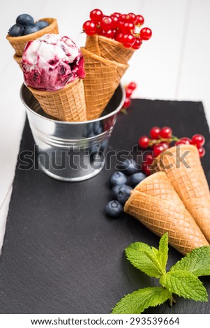 Red fruits ice cream cone on black slate board.