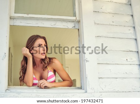lovely brunette female model watches from cottage window
