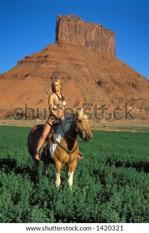 attractive blond female model rides horseback in red rock canyon lands of southern utah