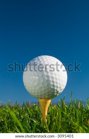 golf ball on tee from ground level, deep blue sky for copy