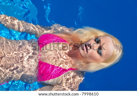 attractive blond female swims on her back in pool