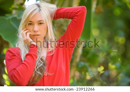 attractive blond model face shot in red sweater at garden with background copy space out of focus