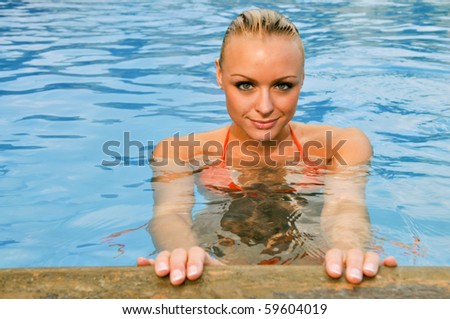 lovely female swimmer in orange bikini in clear blue pool
