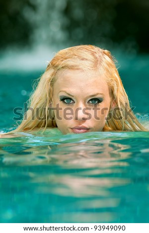 lovely blond female swimmer coming up for air in tropical pool
