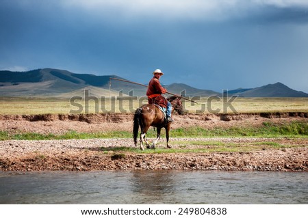 NORTHERN MONGOLIA , MONGOLIA - AUG 06, 2011: Mongolian herder pose fording the river for foreign tourists