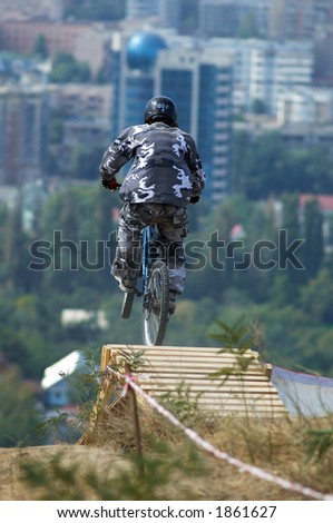 Jump of biker from springboard on background of the city