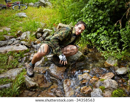 Mountain Biker drinking water from a stream