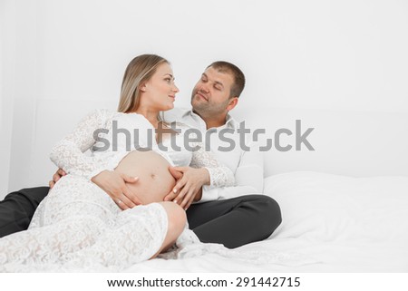 Pregnant lying on the bed with her husband