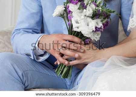 bride and groom holding hands, in the hands of the bride's wedding bouquet