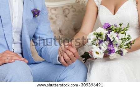 bride and groom holding hands, in the hands of the bride\'s wedding bouquet