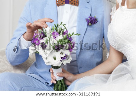 bride and groom holding hands, in the hands of the bride's wedding bouquet
