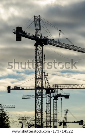 Construction site with cranes at sunset, sunrise, dawn time with the cranes as a silhouette. Vancouver, Canada. Vertical.