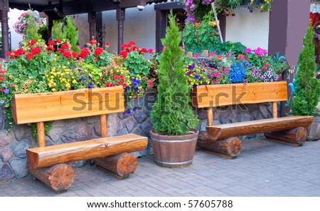 Two funny benches over stone wall and flowers.