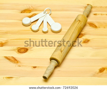 Rolling Pin and Measure cups on Wooden Board.