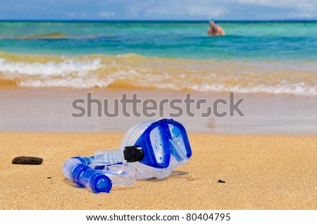 Diving mask and snorkel on gold sand over blue ocean