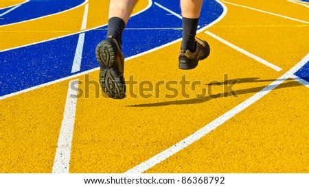 Feet of a running man over colourful running track