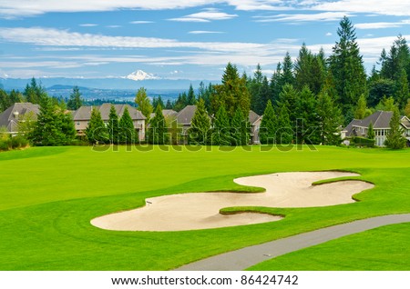 Beautiful golf place with gorgeous green and fantastic snow mountain view over blue sky with white clouds.