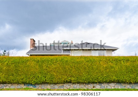 Privacy and Security Concept. House hidden behind the green hedge.