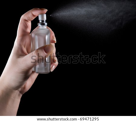 Close up of woman's hand spraying perfume/cologne. Photographed over black background, motion blur.