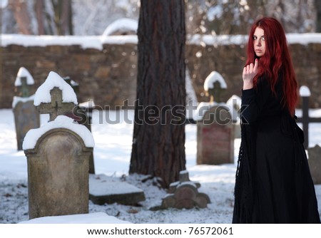 Young women in sorrow with black belcher standing by tomb stone.