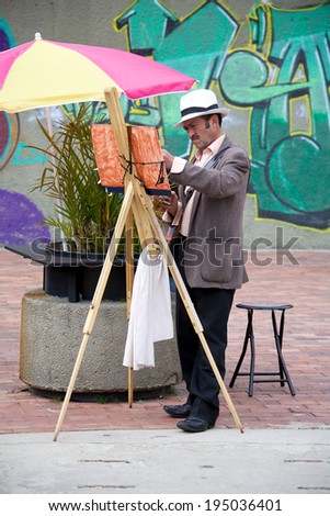 BOGOTA, COLOMBIA - APRIL 06, 2014: Unidentified artist creating paintings in the streets of Usaquen in Bogota Colombia. Usaquen was declared a national monument in 1987.