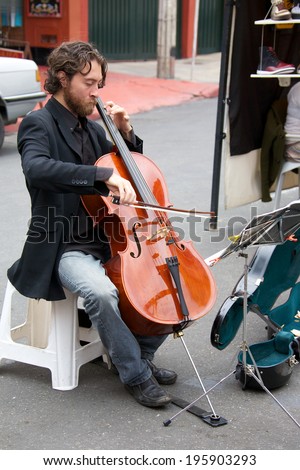 BOGOTA, COLOMBIA - APRIL 06, 2014: An unidentified musician playing cello for money in the streets of Usaquen in Bogota Colombia. Usaquen was declared a national monument in 1987.