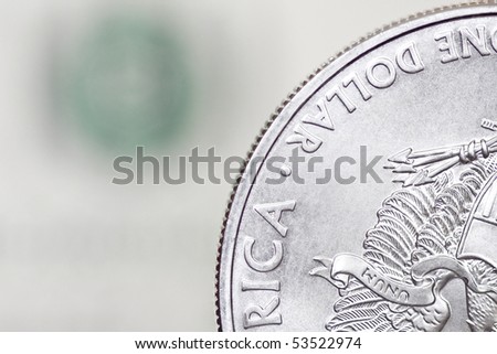 Silver shiny one dollar coin on a blurry background of dollar bill
