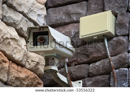 Security surveillance camera on side of building.