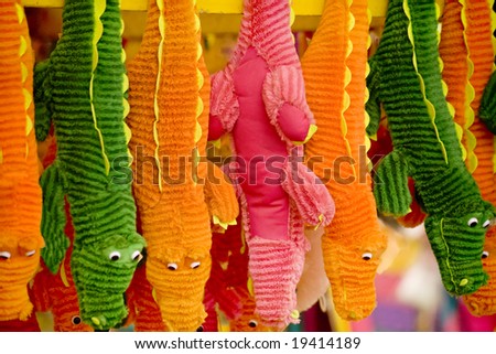 Stuffed plush animals in various colors hanging in a vendor\'s stall.