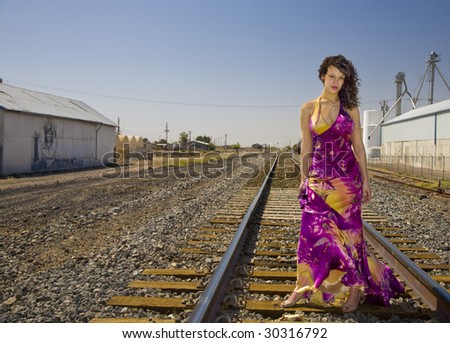 Attractive African American fashion model in a gown  photographed on railroad tracks in an urban  industrial location.