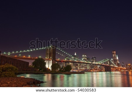 The Brooklyn Bridge lit up at night in front of the Manhattan skyline in New York City.