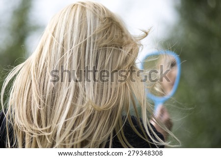 beautiful blonde girl with a mirror in nature