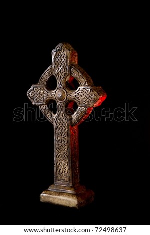 Celtic Cross - photographed on a black background. The cross is accented by red candle light to symbolize Jesus\'s blood.
