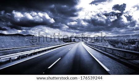 Road scenery. Travel concept.Cloudy sky and high road in blue toned