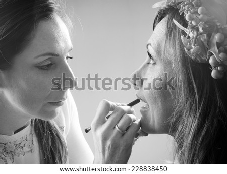make up artist applying lips line to the model with a pencil in black and white