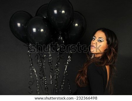 portrait of a Young beautiful girl with long hair posing with black balloons isolated on black background