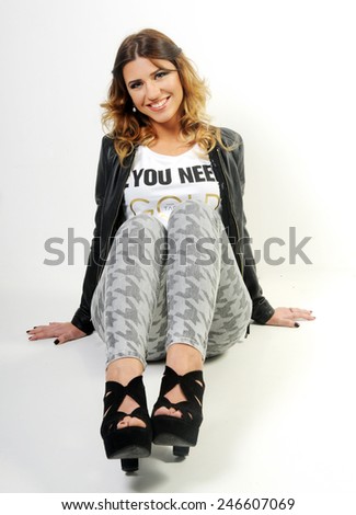 portrait of a Young beautiful funny smiling caucasian teen girl seating on the White background leaning backwards holding her legs in front of her chest