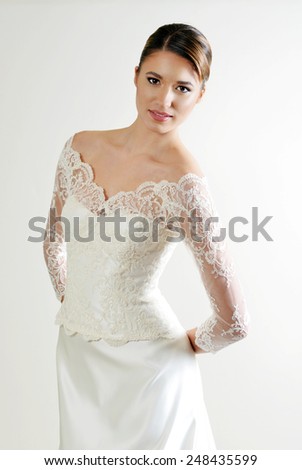 portrait of a beautiful Young slim bride with a perfect figure and perfect make up wearing a White lace wedding gown with long sleeves