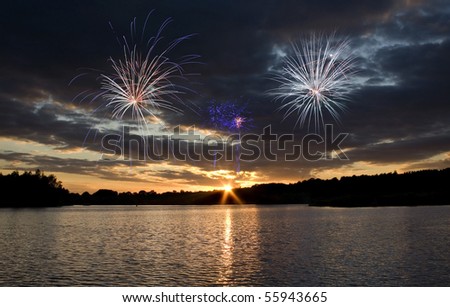 Holiday fireworks at sunset over a picturesque lake. Fourth of July.