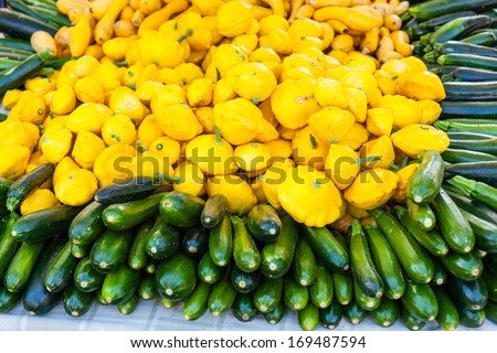 Pile of yellow button squash and zucchini for sale at local farmers market.