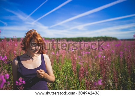 The girl thinking on the middle of the field of Chamaenerion with lines cloud on sky
