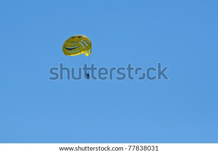 A smiley face yellow parasail in mid air over the ocean