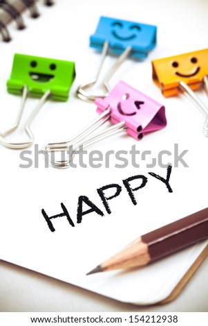 happy word on paper with pencil and clips