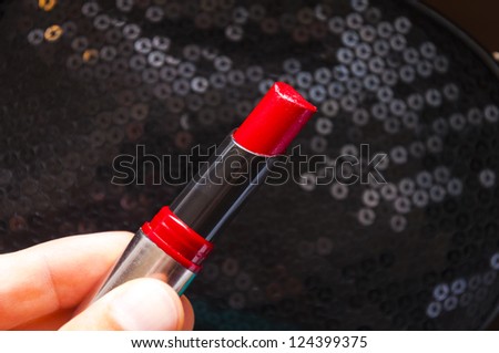An image of red lipstick in hand