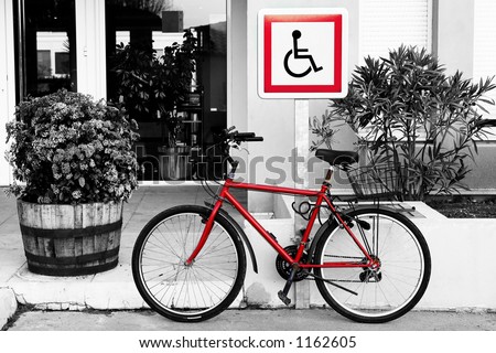 Bicycle in front of a sign.  Black and white background. Bicycle and sign is red.  Photographic effect