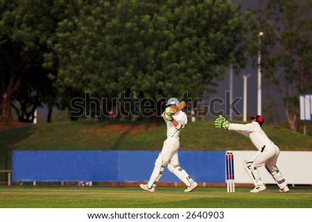 Cricketers playing in the late afternoon, Batsman hitting ball, wicketkeeper trying to catch