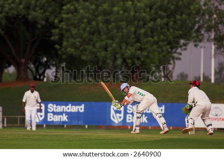 Cricketers playing in the late afternoon, Batsman hitting ball, wicketkeeper trying to catch - Editorial us only