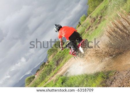 Young man riding around on his dirtbike doing tricks and getting dirty. Movement on edges of motorbike - Focus on water spray